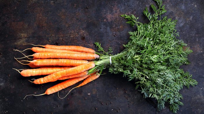 Carrot. A bunch of young carrots with parsley on a dark background.