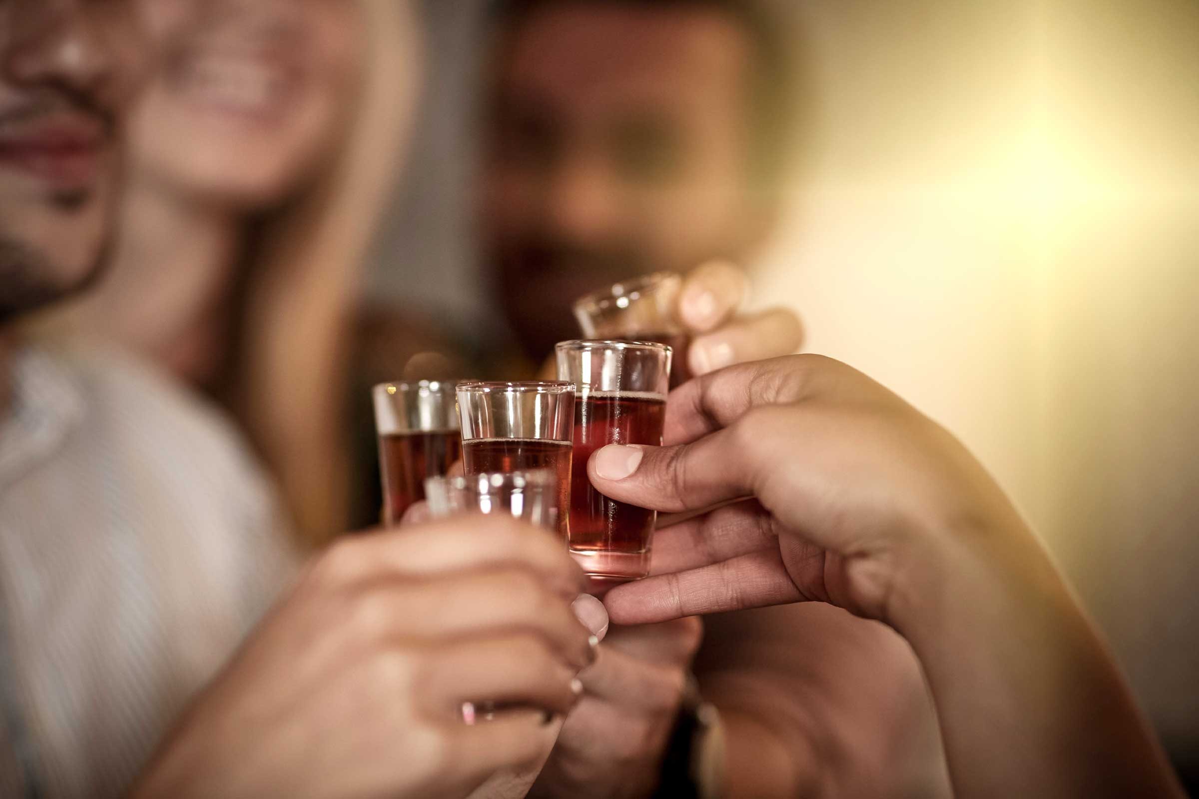 closeup of hands holding shot glasses