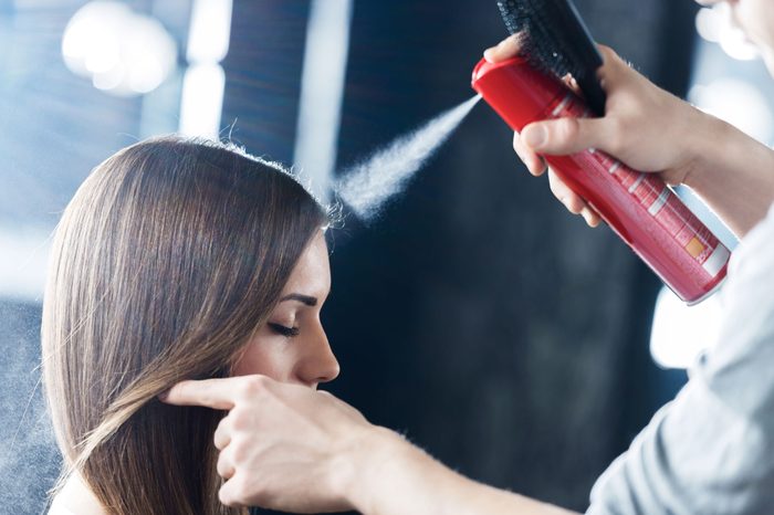 Woman with brown hair getting her hair done (and hair sprayed) at the salon.