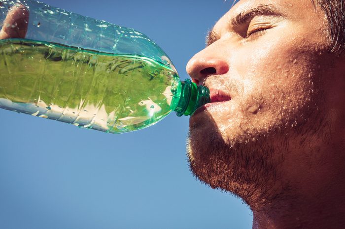 Man drinking a sports drink outdoors.