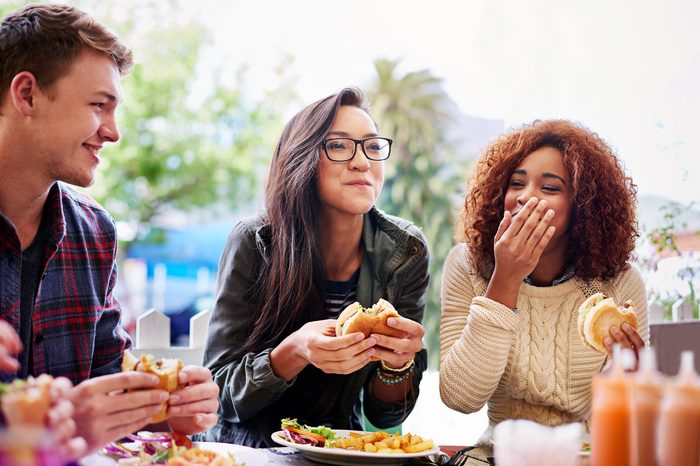 Group of friends laughing while eating lunch.