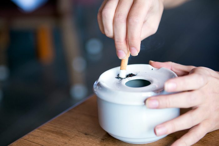 Person stubbing their cigarette out in an ashtray.