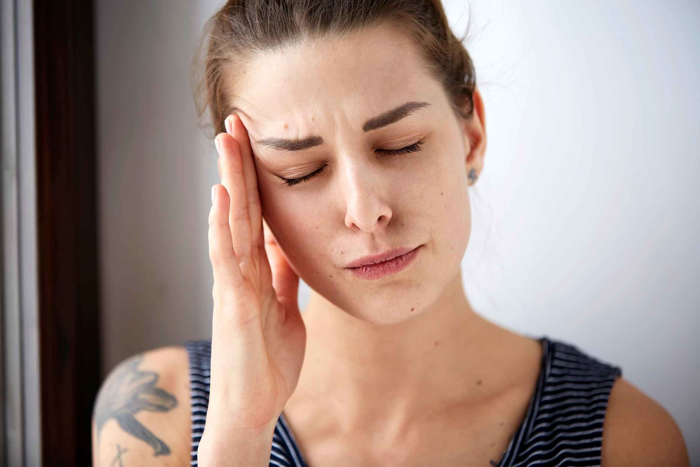 woman massaging her temple with eyes closed