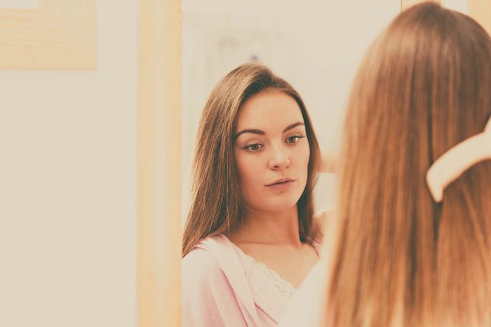 Woman combing her hair in the mirror.