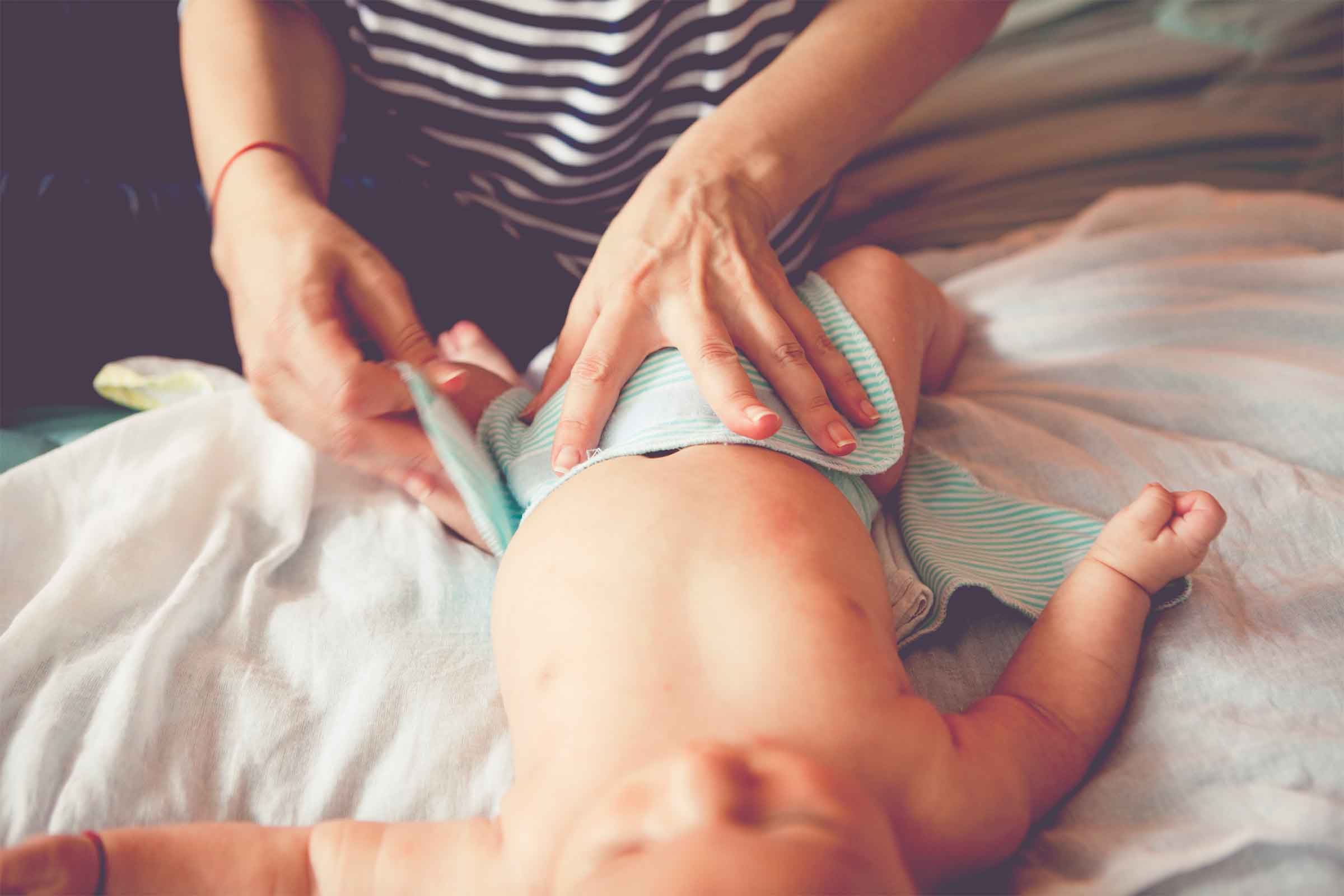 woman putting on baby's diaper