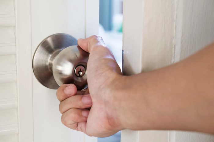 Person with their hand on a doorknob opening a door.