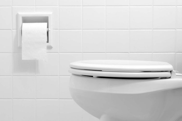 White bathroom with a white toilet and white tile wall.