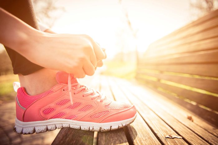 woman lacing up athletic shoe