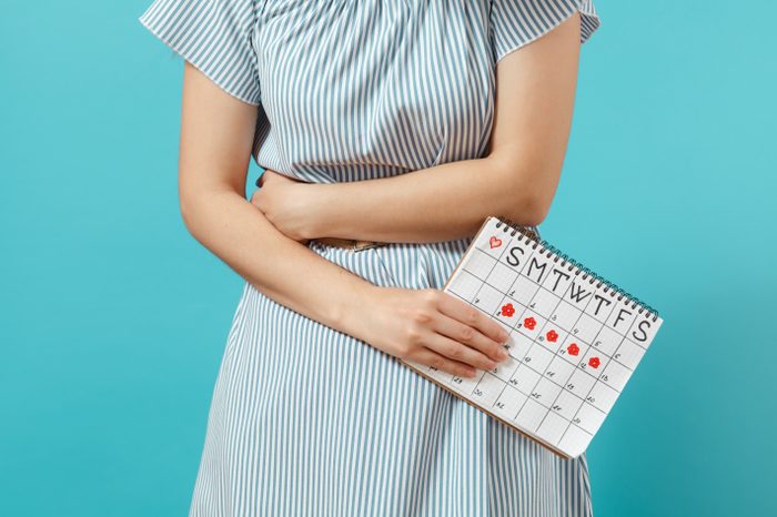 woman holding stomach with menstrual calendar period