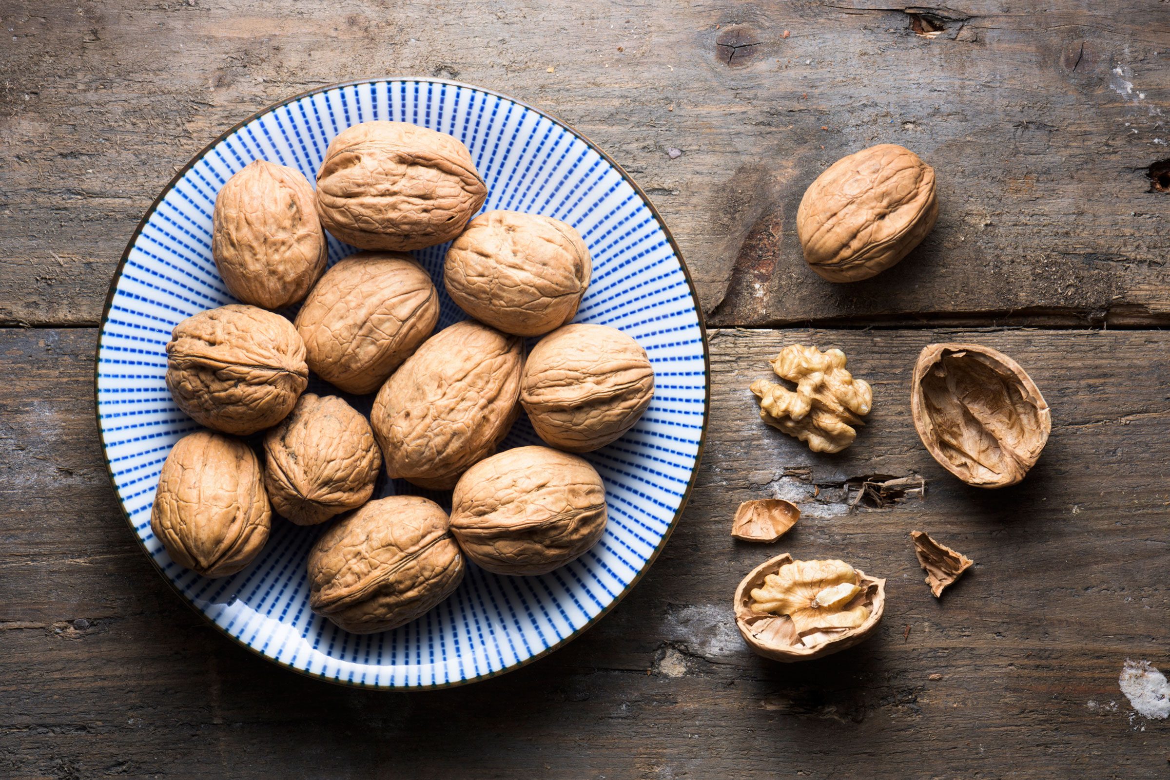 whole and shelled walnuts on a a blue plate