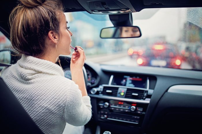 girl woman putting lipstick on in car mirror