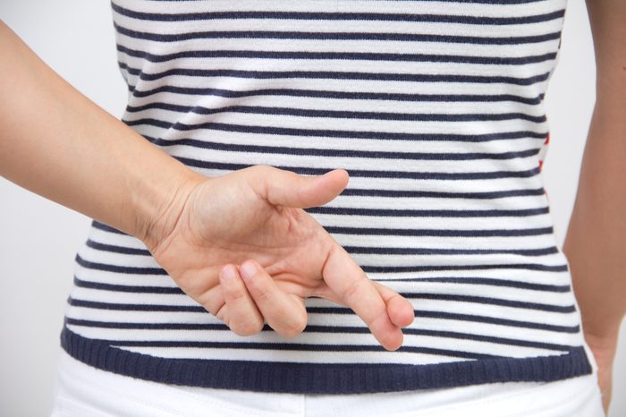 Woman crossing fingers behind her back lie lying crossed