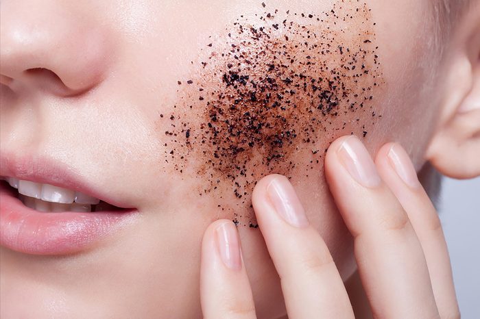 A woman exfoliating her skin with brown exfoliating gel.