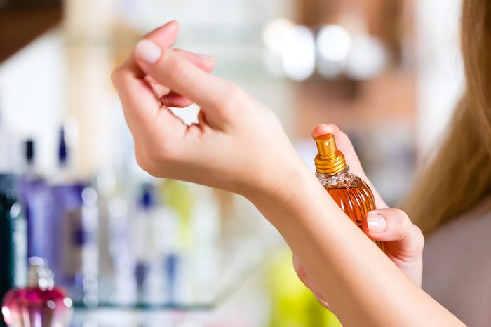 A woman applying fragrance to her wrist.