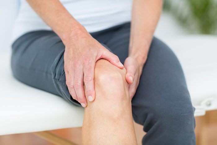 person sitting on the edge of a bed holding knee