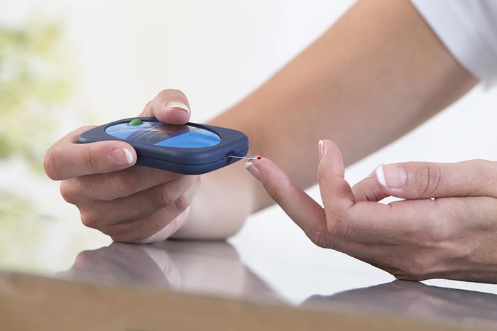 woman testing her blood sugar with finger-stick device