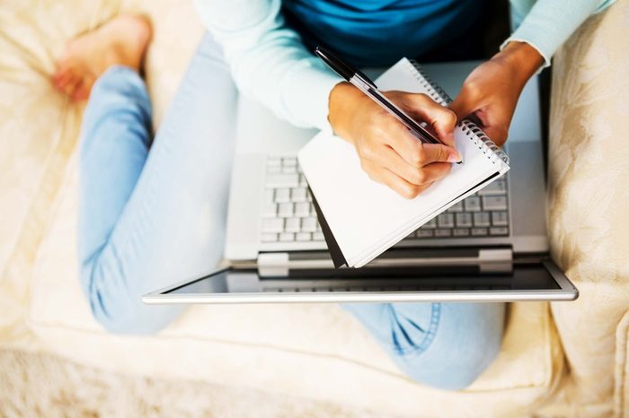 woman with computer in lap taking notes