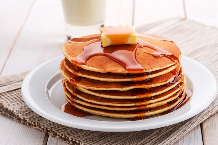 Stack of pancakes with butter and syrup on plate