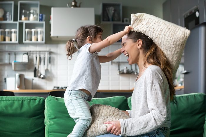 Mommy and kid daughter having pillow fight together, young babysitter nanny playing funny game with kid girl at home, happy mother and child enjoy spending time together, family leisure fun activity