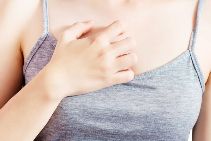 Woman in a tank top holding her hand to her chest