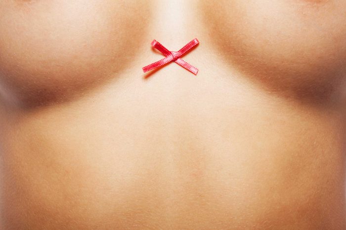 close up of woman's naked torso with cancer ribbon between breasts