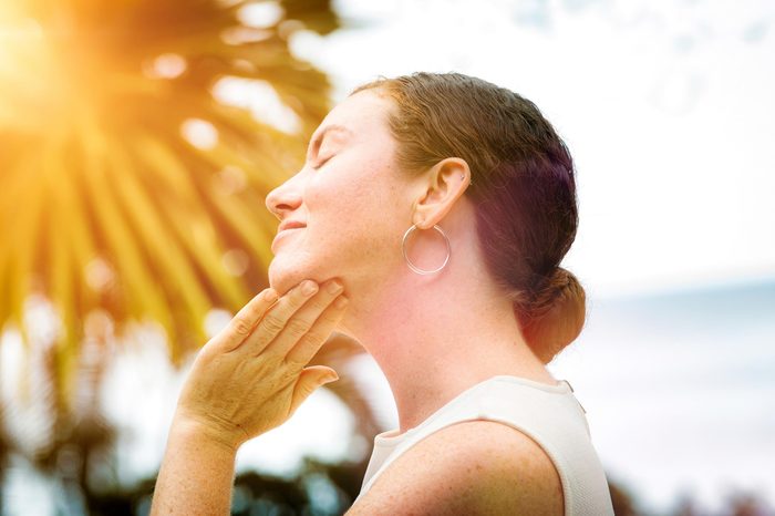 woman rubbing lotion on her neck