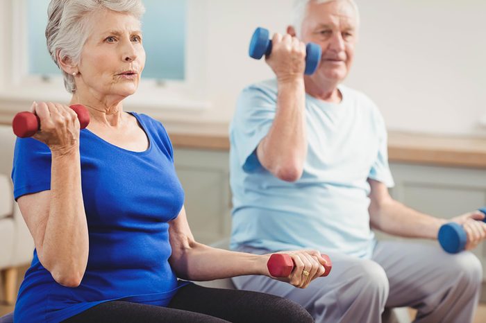 two older people lifting weights