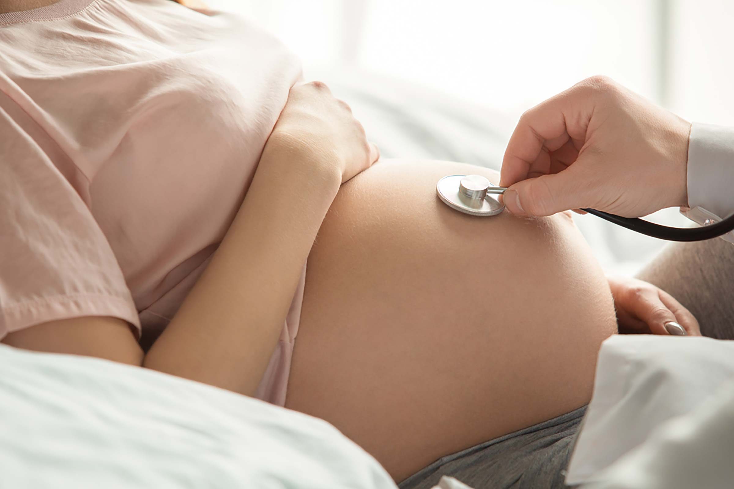 doctor checking a pregnant woman's belly with a stethoscope