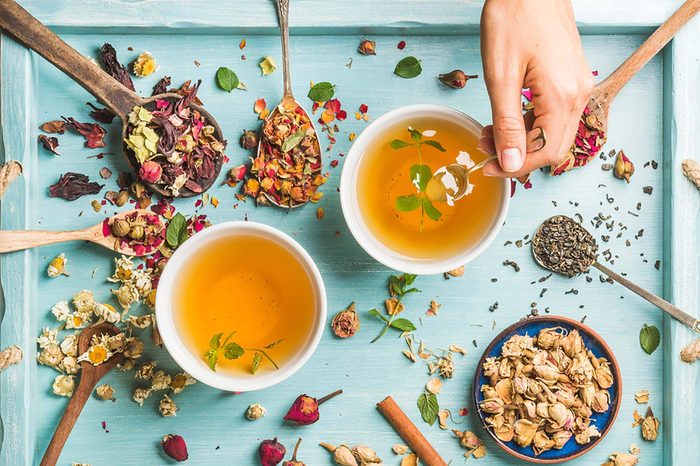 Passion tea herbs scattered on a tray and in tea cups