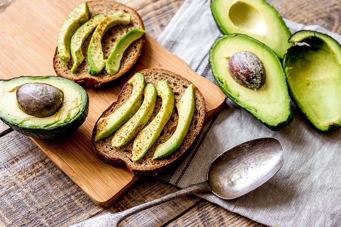 halved avocados and sliced avocado on toast