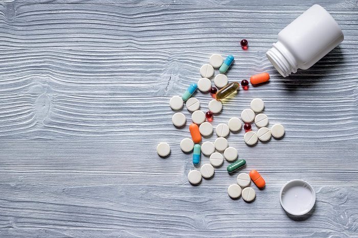 Vitamins and supplements spilling out of a bottle onto a table