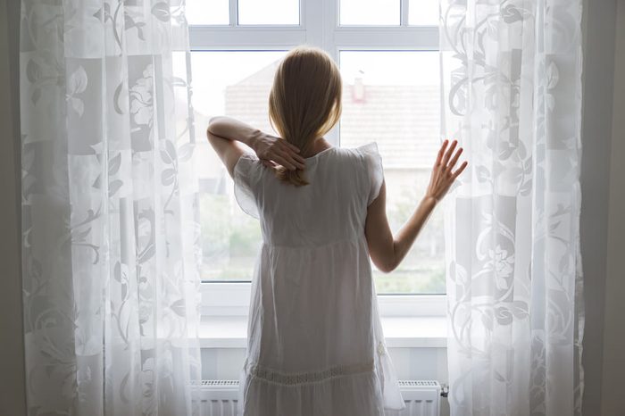 sad lady standing by a window