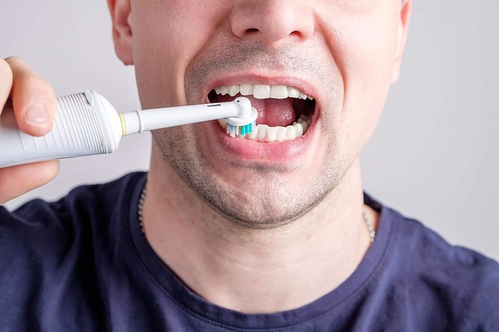 man using an electric toothbrush