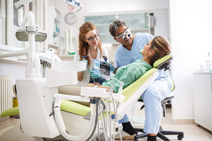 Dentist and assistant talking to patient in chair