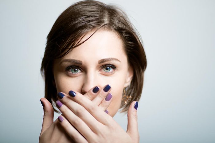 Pretty slender girl covers her mouth with her hands