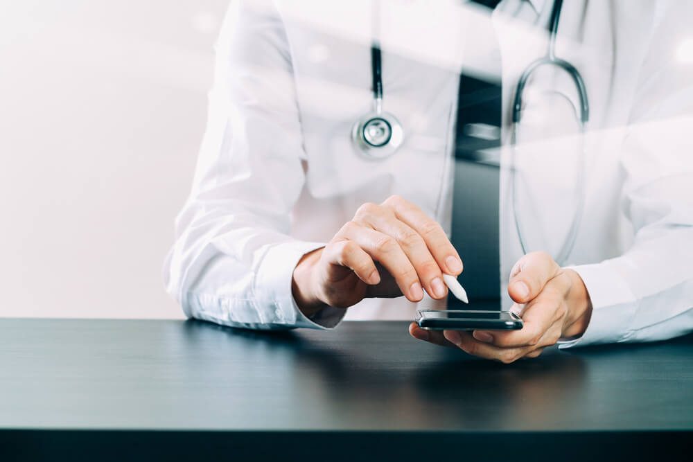 doctor with stethoscope working on a smartphone