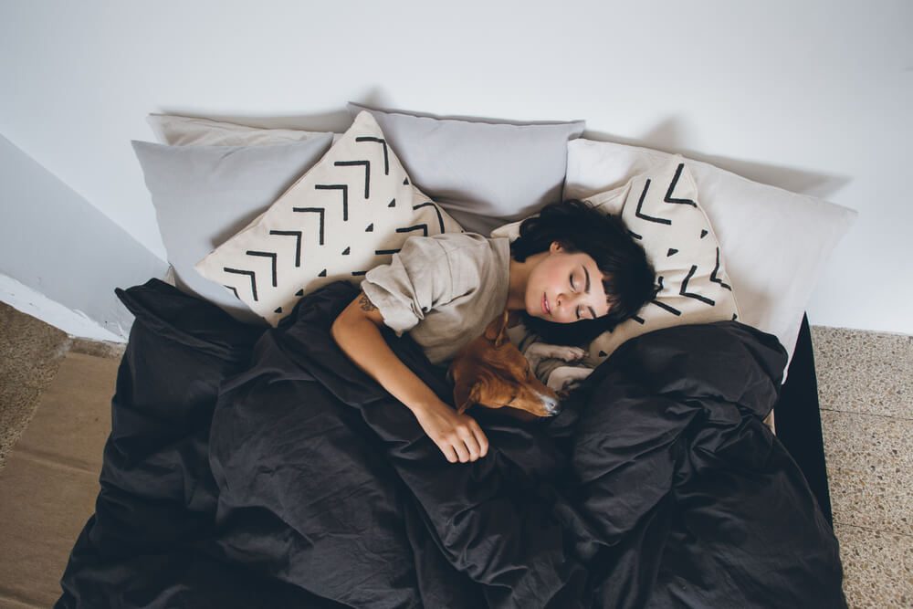 woman sleeping in bed with dog