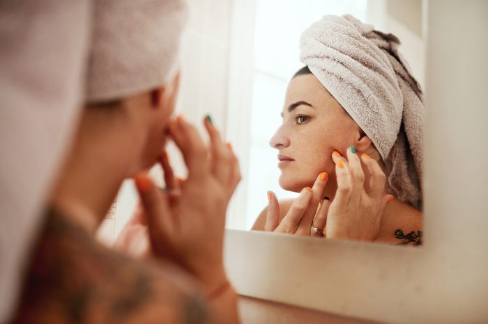 woman inspecting her skin in mirror after taking a shower