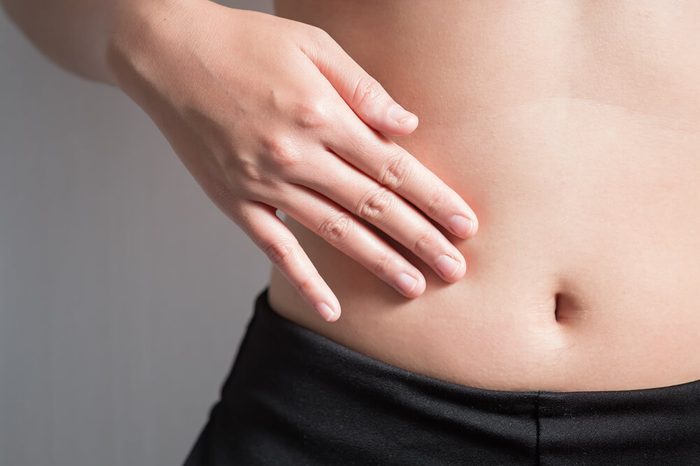 Woman with her hand on her bare stomach 