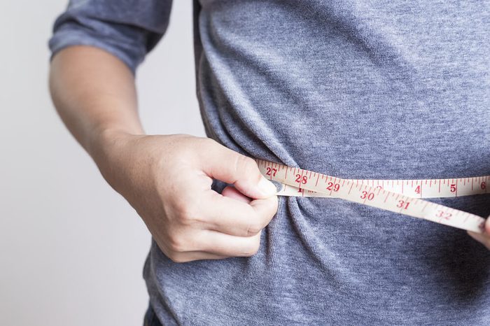 Person checking waistline with a tape measure