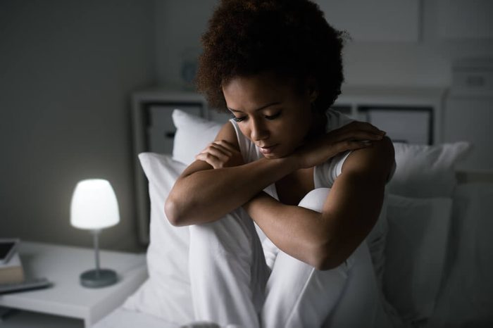 Sad depressed woman sitting in her bed late at night