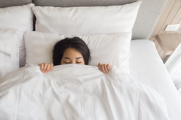 Close-up of young woman sleeping under white blanket 