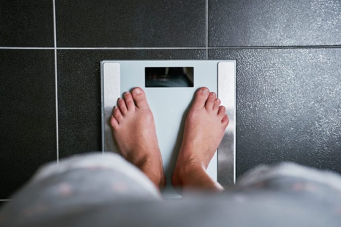 Female bare feet stepping on a weight scale