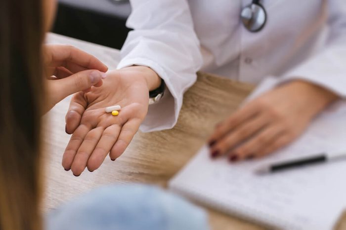 Female nurse give pill to young patient