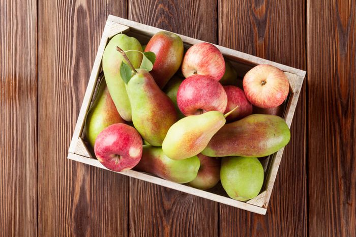 Pears and apples in wooden box on table