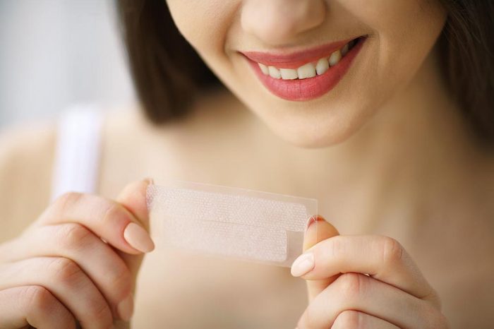 Teeth Whitening. Beautiful Smiling Woman Holding Whitening Strip. High Resolution Image