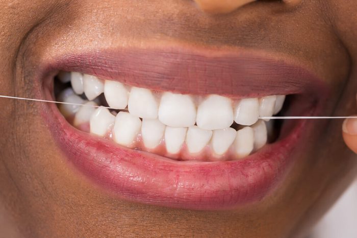 A woman flossing her teeth with dental floss.