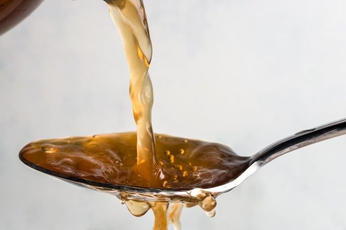 Apple cider vinegar being poured onto a spoon.