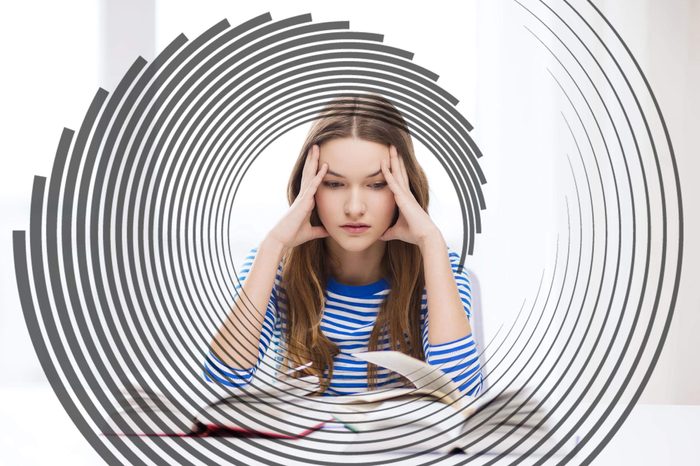 woman holding her head in her hands, staring at open books