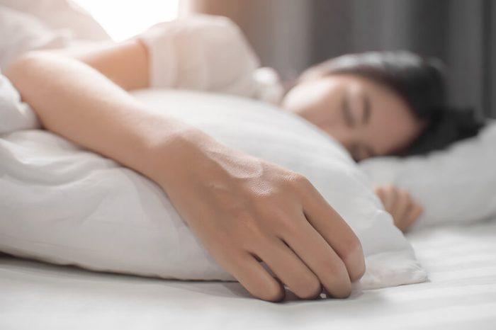 Woman sleeping on her side in a white bed